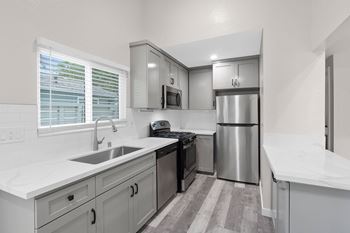 A white kitchen with stainless steel appliances and white counter tops